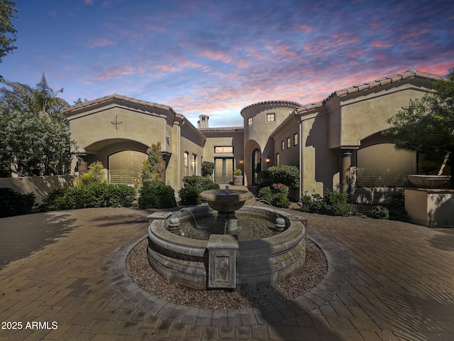 mediterranean / spanish home with curved driveway, stucco siding, and a tiled roof