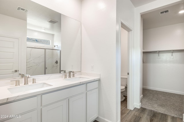 bathroom with hardwood / wood-style flooring, toilet, an enclosed shower, and vanity