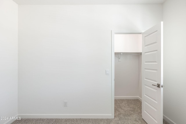 unfurnished bedroom with light carpet and a closet