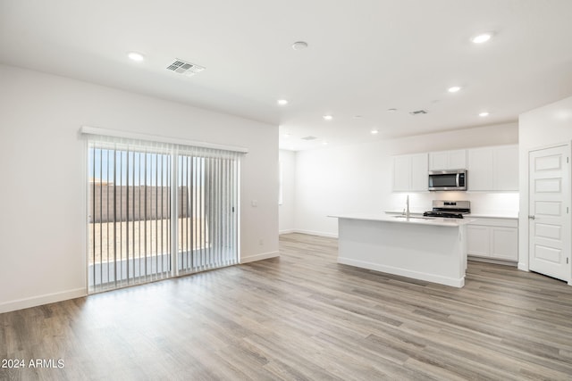 kitchen featuring a center island with sink, white cabinets, stainless steel appliances, and light hardwood / wood-style flooring