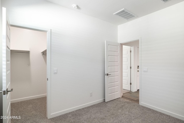 unfurnished bedroom with carpet flooring, a spacious closet, and a closet