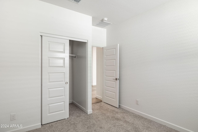 unfurnished bedroom with light carpet and a closet