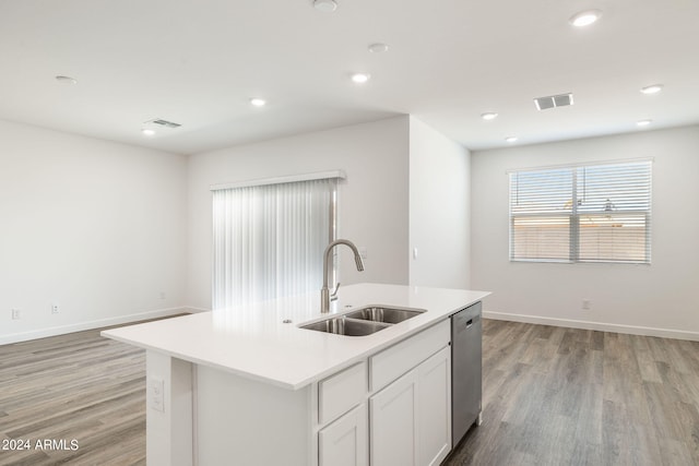 kitchen with light wood-type flooring, a kitchen island with sink, sink, dishwasher, and white cabinetry