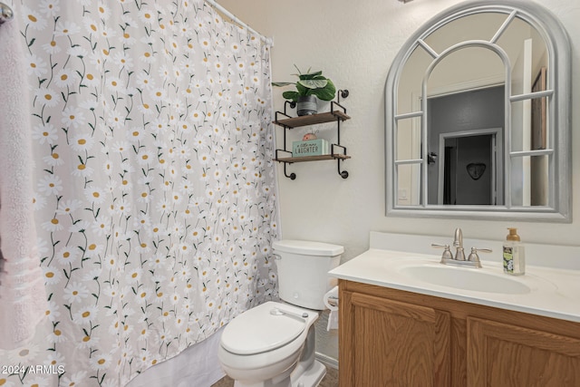 bathroom with walk in shower, vanity, and toilet