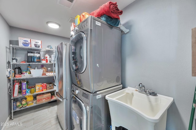 laundry room featuring stacked washer / drying machine and sink