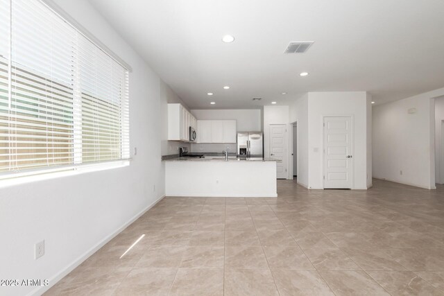 3036 E Riding Boot Way, San Tan Valley, AZ 85140 - kitchen with stainless steel fridge with ice dispenser, a peninsula, recessed lighting, white cabinetry, and open floor plan