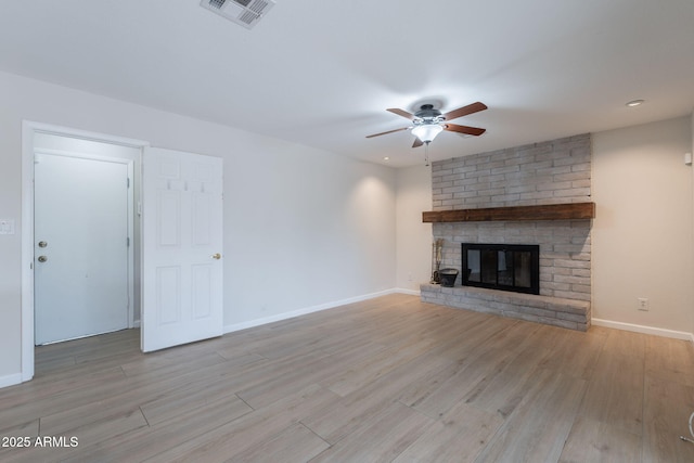 unfurnished living room with a ceiling fan, light wood-style flooring, a brick fireplace, and baseboards