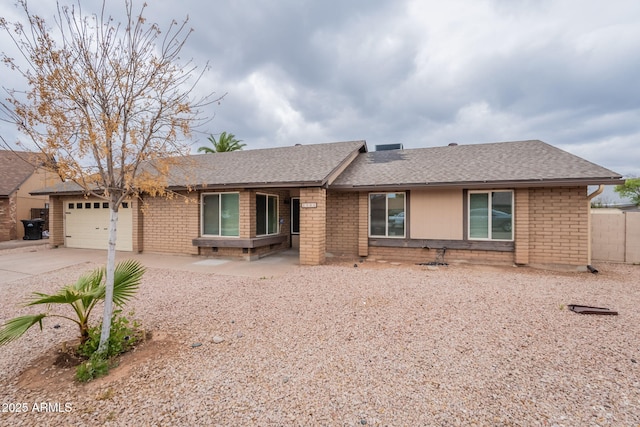 ranch-style home featuring roof with shingles, driveway, and brick siding