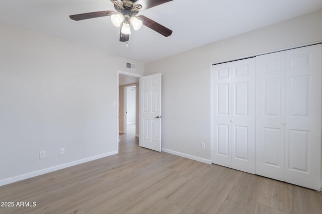 unfurnished bedroom with light wood-type flooring, baseboards, a closet, and ceiling fan