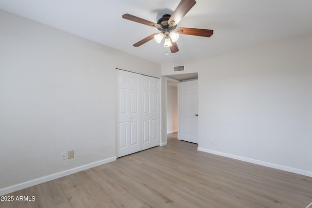 unfurnished bedroom featuring light wood-type flooring, baseboards, a closet, and a ceiling fan