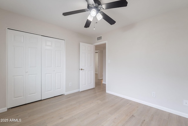 unfurnished bedroom featuring light wood finished floors, baseboards, a closet, and a ceiling fan