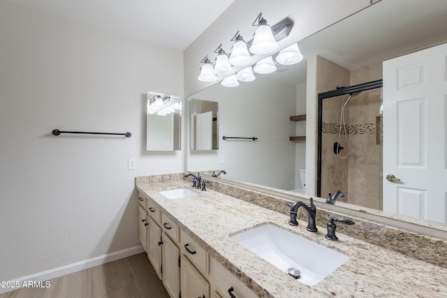 bathroom with toilet, a stall shower, double vanity, wood finished floors, and baseboards