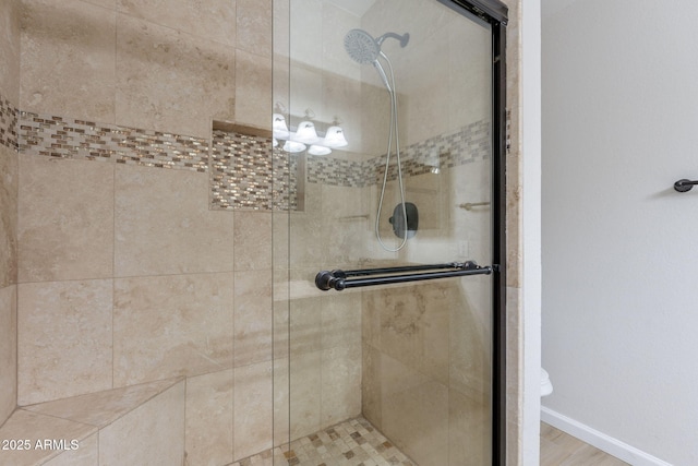 bathroom with a stall shower, baseboards, and toilet