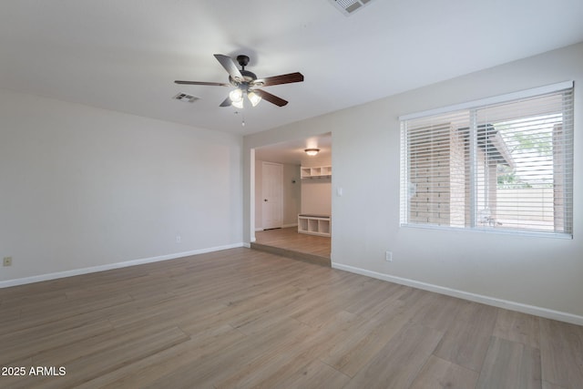 empty room featuring a ceiling fan, light wood-style flooring, and baseboards