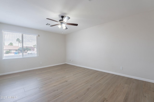 spare room with ceiling fan, light wood-style floors, and baseboards
