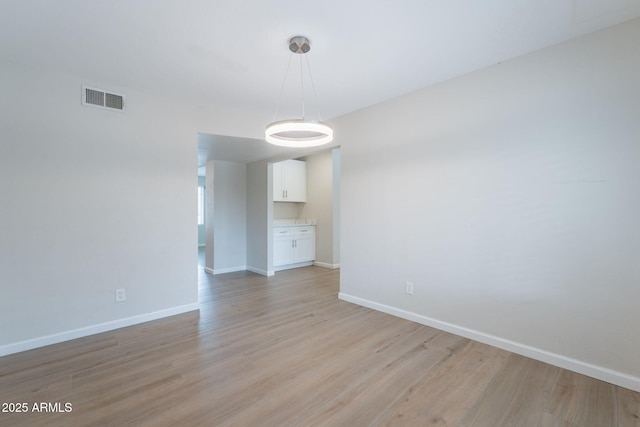 unfurnished room with baseboards and light wood finished floors