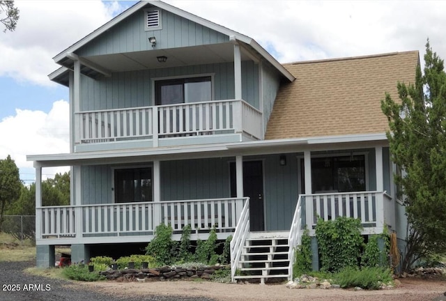 view of front of home featuring a balcony, covered porch, stairs, and roof with shingles