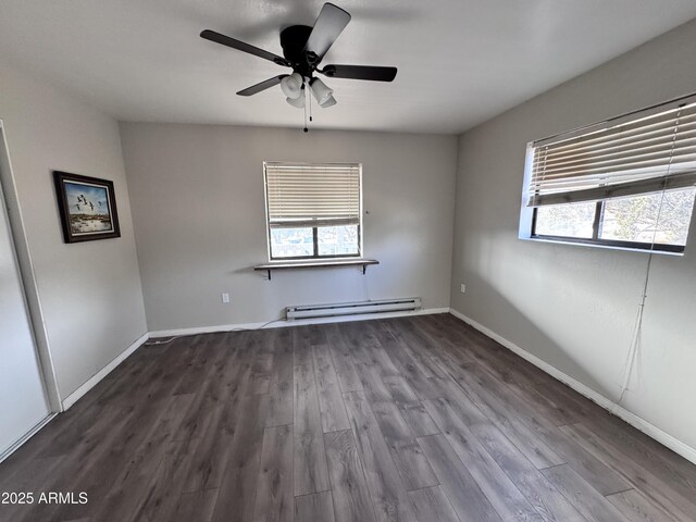 empty room featuring a wealth of natural light, a baseboard radiator, and wood finished floors