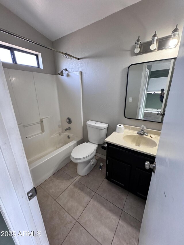 full bath featuring toilet, vanity, vaulted ceiling, tile patterned floors, and washtub / shower combination