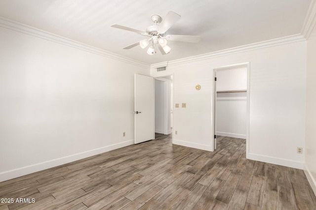 38 E Calavar Rd, Phoenix, AZ 85022 - unfurnished bedroom featuring crown molding, wood finished floors, a ceiling fan, a closet, and a spacious closet