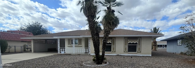 ranch-style home featuring brick siding, covered porch, an attached garage, fence, and driveway