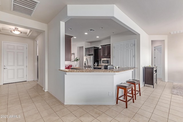 27105 W Marco Polo Rd, Buckeye, AZ 85396 - kitchen featuring stainless steel appliances, light tile patterned flooring, light stone counters, a breakfast bar area, and baseboards