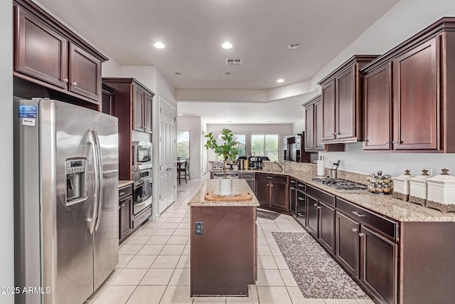 27105 W Marco Polo Rd, Buckeye, AZ 85396 - kitchen with appliances with stainless steel finishes, a peninsula, light stone counters, light tile patterned flooring, and a kitchen island