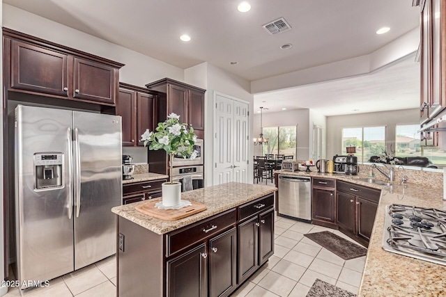 27105 W Marco Polo Rd, Buckeye, AZ 85396 - kitchen featuring appliances with stainless steel finishes, light tile patterned flooring, a kitchen island, dark brown cabinetry, and recessed lighting