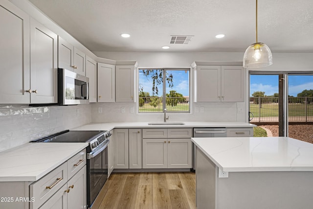 1236 S Boulder St Unit C, Gilbert, AZ 85296 - kitchen featuring stainless steel appliances, light wood-style floors, decorative backsplash, recessed lighting, and hanging light fixtures