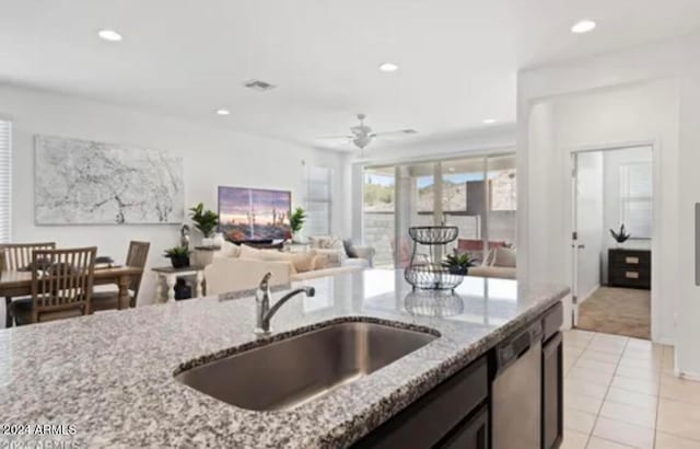 kitchen featuring stainless steel dishwasher, sink, light stone countertops, and light tile patterned flooring