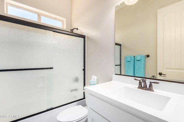 bathroom featuring combined bath / shower with glass door, toilet, and vanity