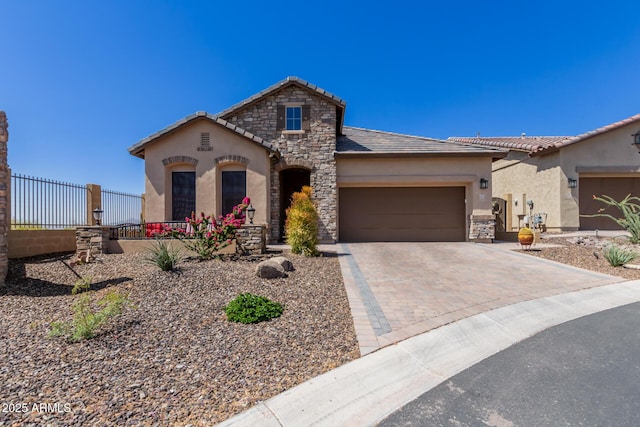 view of front of property with stucco siding, driveway, a garage, a tiled roof, and stone siding