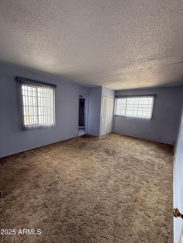 empty room featuring a textured ceiling and carpet flooring