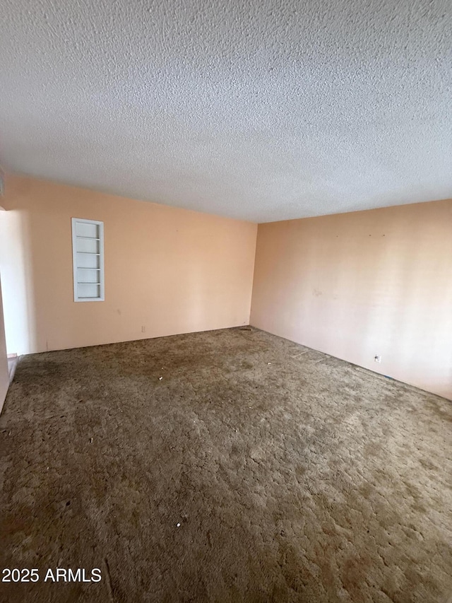 empty room with a textured ceiling and carpet flooring