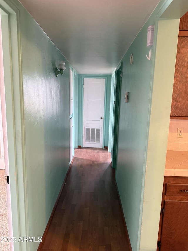 hall with visible vents, dark wood finished floors, and baseboards