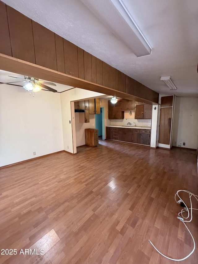 unfurnished living room featuring dark wood-style floors, ceiling fan, and baseboards