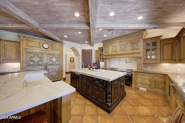 kitchen featuring a spacious island, beam ceiling, sink, light tile patterned floors, and tasteful backsplash