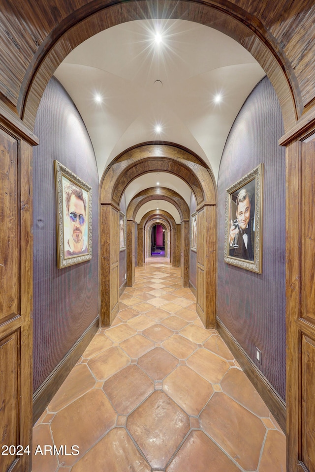 hallway with lofted ceiling and wooden walls