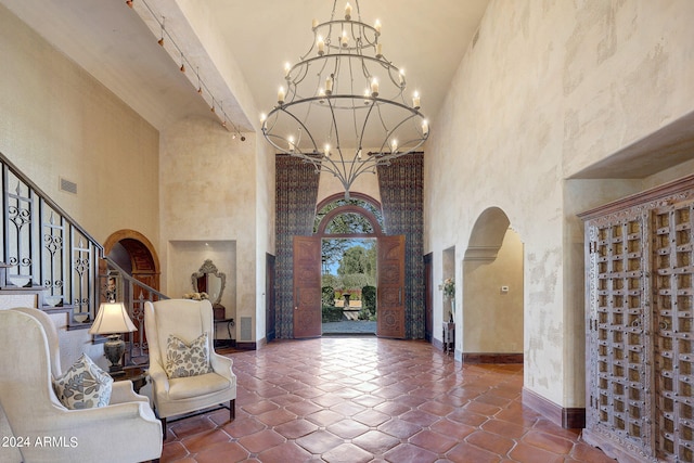 entrance foyer featuring decorative columns, a towering ceiling, and tile patterned flooring