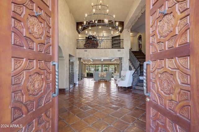 tiled entryway featuring a chandelier and a towering ceiling