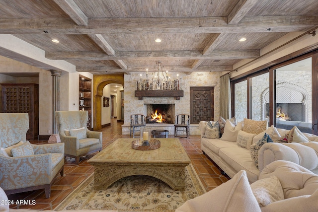 living room with a stone fireplace, beamed ceiling, coffered ceiling, and decorative columns