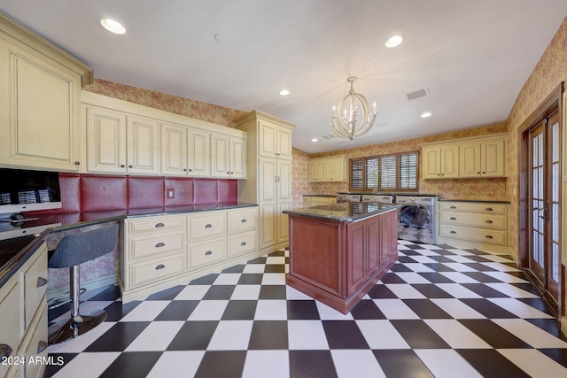 kitchen featuring washer / dryer, a kitchen island, hanging light fixtures, a breakfast bar, and an inviting chandelier