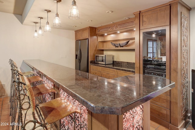 kitchen featuring a kitchen bar, light tile patterned flooring, hanging light fixtures, and stainless steel appliances