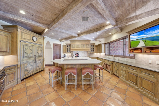 kitchen with tasteful backsplash, lofted ceiling with beams, a kitchen bar, and a kitchen island