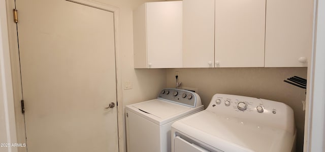 washroom featuring cabinets and washer and clothes dryer