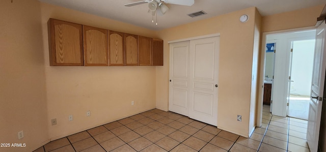 unfurnished bedroom with ceiling fan, light tile patterned floors, and a closet