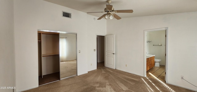 unfurnished bedroom featuring ensuite bath, ceiling fan, light colored carpet, vaulted ceiling, and a closet