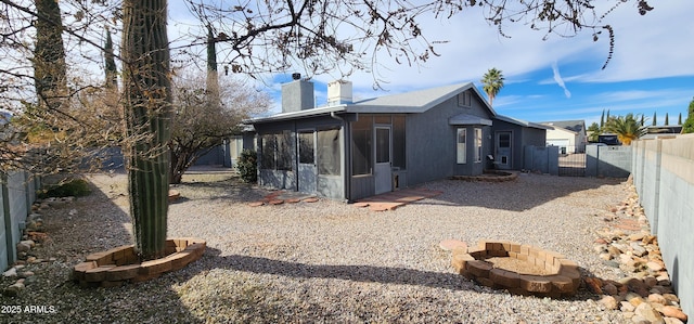 back of property with a fire pit and a sunroom