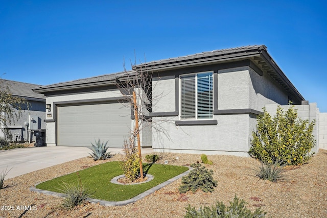 view of front of house with a garage, concrete driveway, and stucco siding