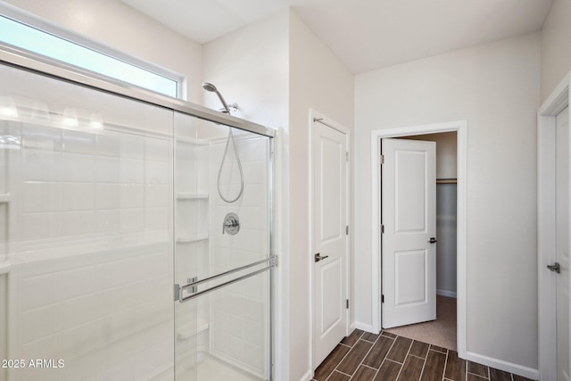 full bath with baseboards, a closet, a shower stall, and wood tiled floor